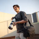 Sling-style camera bag with crossbody strap and laptop fit