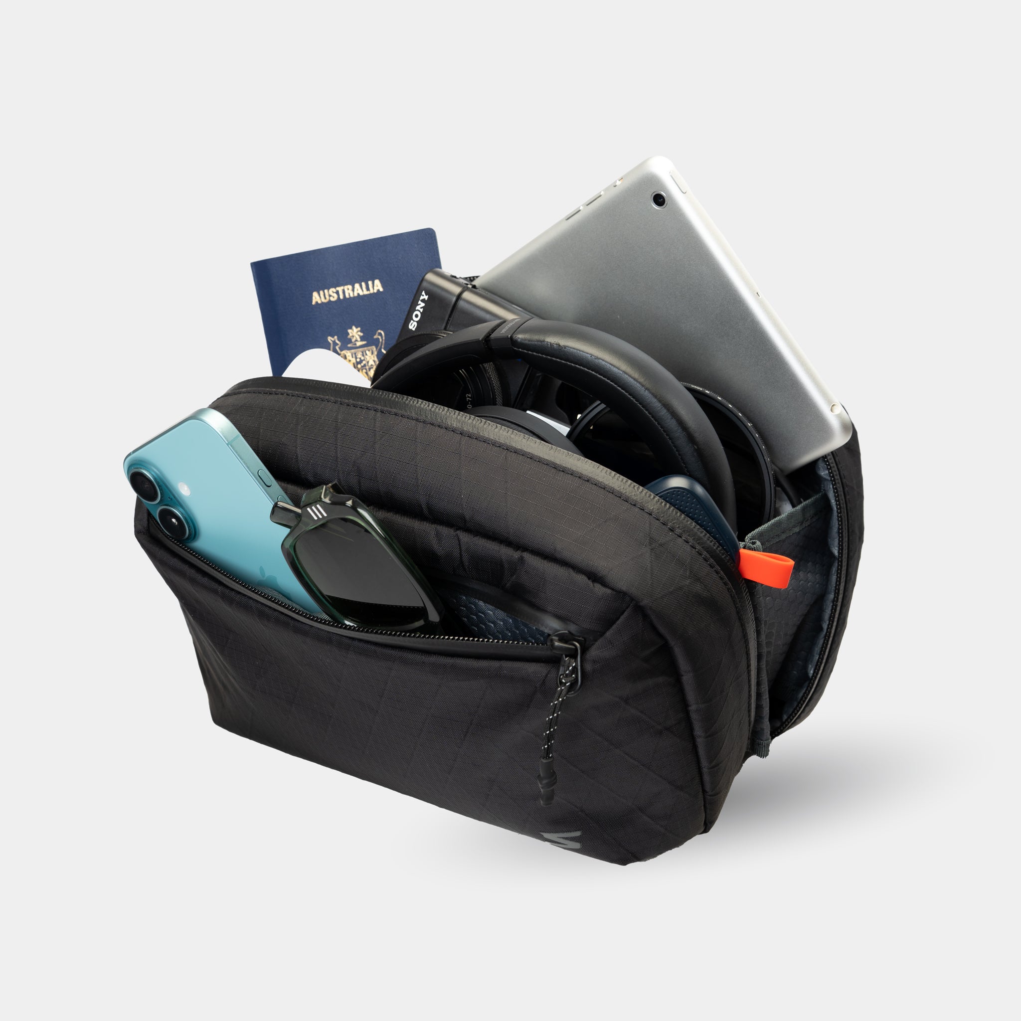 Slim sling bag holds travel tech accessories. Designed to fit inside any carry-on or tote.
